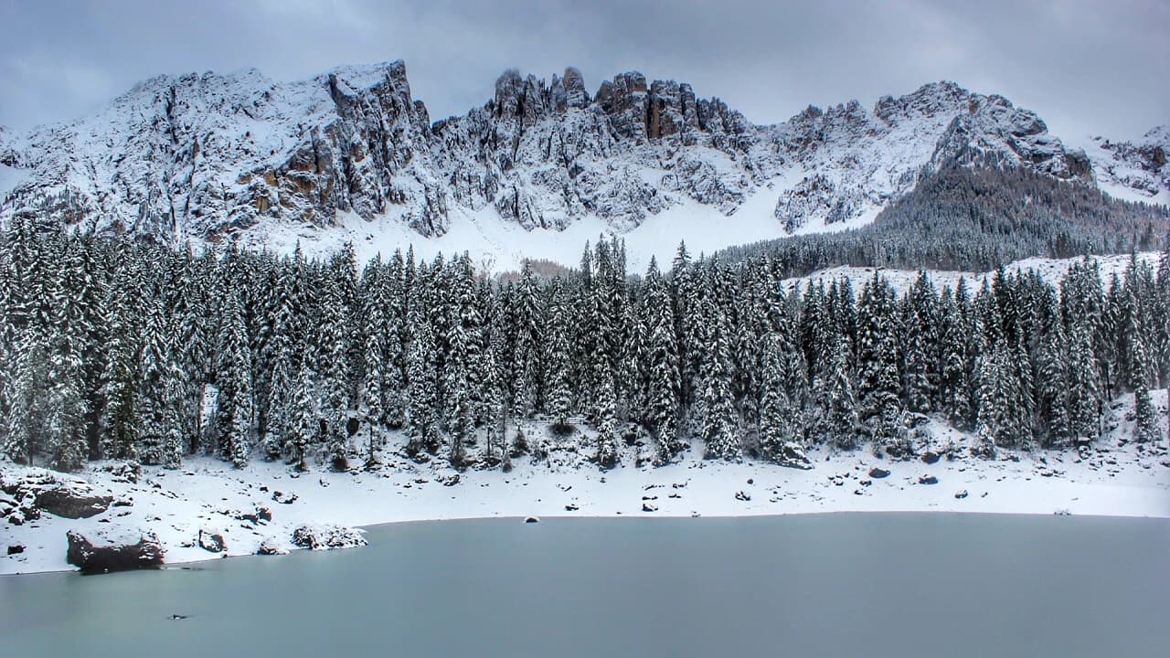 Lago di Carezza ghiacciato in inverno con riflesso del Latemar