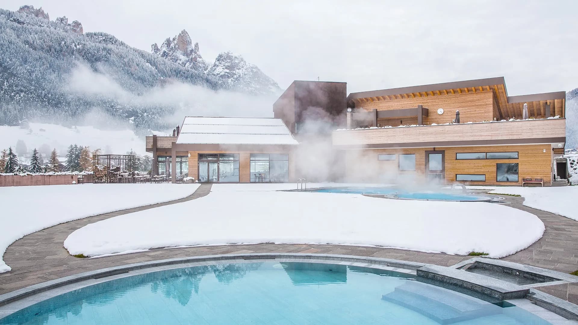 Piscina esterna delle QC Terme Dolomiti con vista sulle Dolomiti innevate